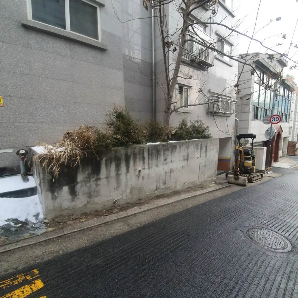 담장철거 — 철거 전 담장과 골목에 진입한 소형 굴삭기