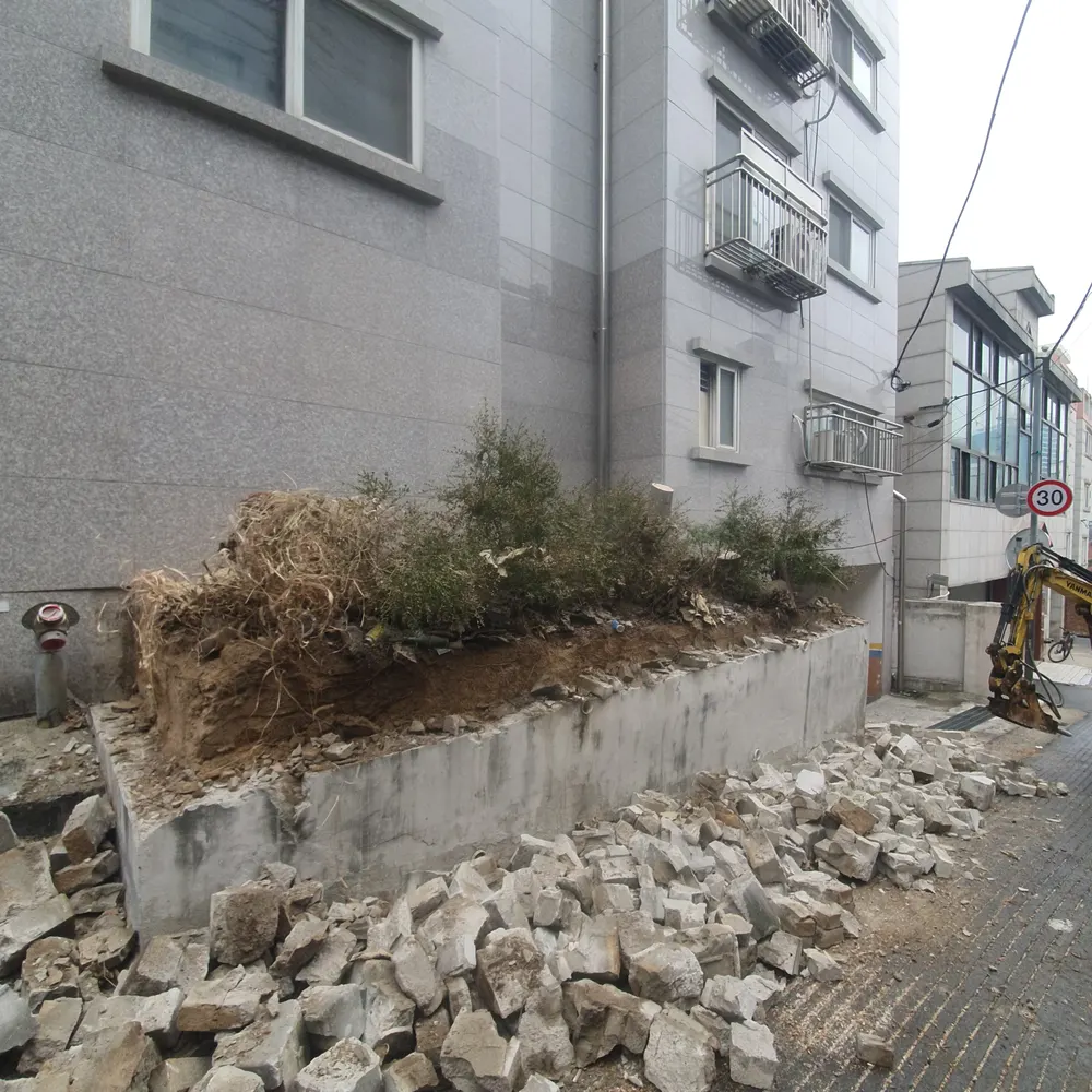 담장철거 — 철거 완료 후 쌓인 잔재와 굴삭기
